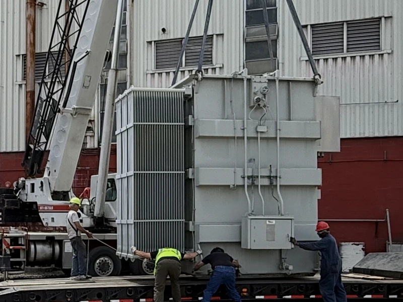 A crane rigging a substation transformer with a crew in protective gear