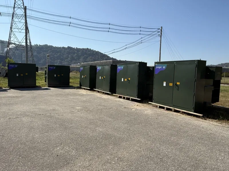 A row of padmount transformer cabinets beneath transmission lines