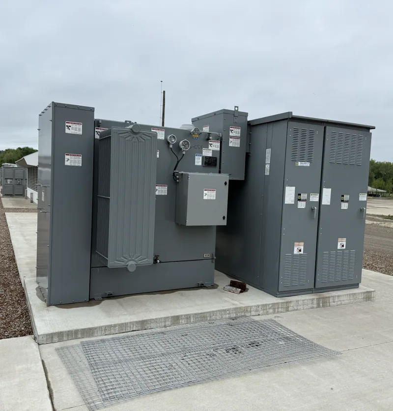 A grey padmount transformer and secondary cabinet on a concrete pad