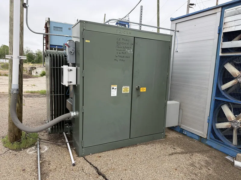 A green padmount transformer cabinet on a concrete pad