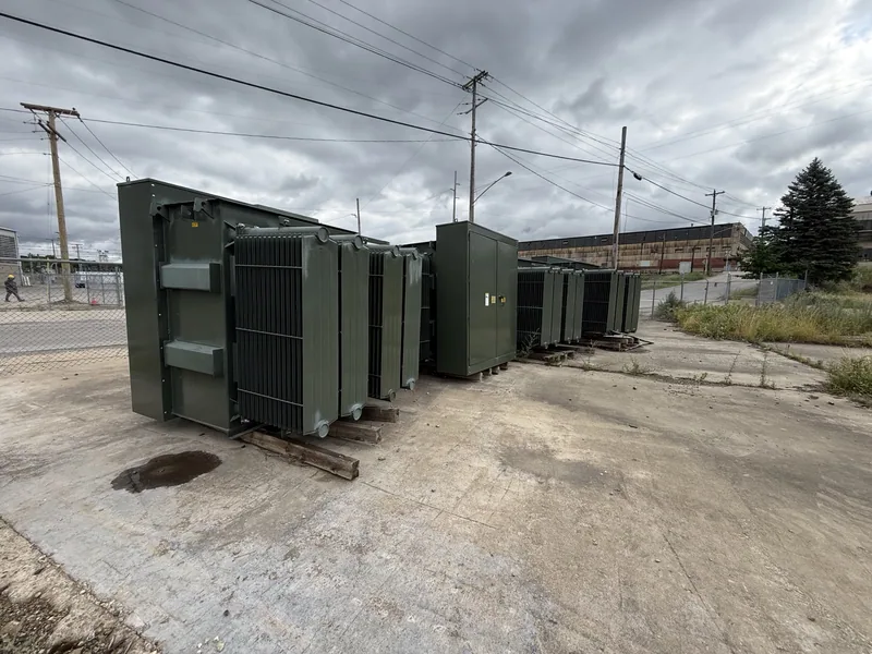A row of green padmount transformers staged in a yard